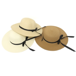 Detail showing three colors of woven sun hats with black ribbon bows in cream and tan