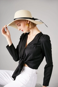 Detailed view of a summer straw sun hat with black ribbon worn with a V-neck blouse