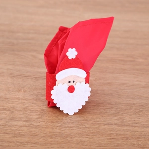 Close-up of Santa Claus felt napkin ring holder with red cloth napkin on wooden table