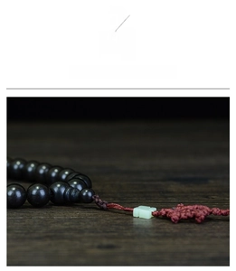 Close-up of black ebony 108 prayer beads with a green jade pendant and red knot