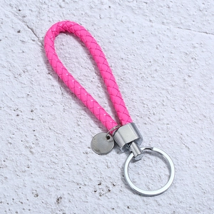 Detail of bright pink braided leather keychain with polished silver metal ring and tag