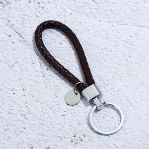 Macro view of hand-woven dark brown leather keychain with polished silver metal ring