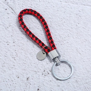 Detail of red and black braided leather keychain with polished silver metal ring and tag