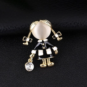 Detail of a gold girl brooch with cat eye stone head and black white enamel dress