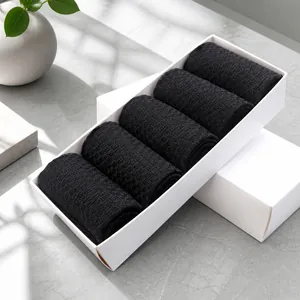 Fünf Paar schwarze Bambusfasersocken ordentlich gerollt in weißer Geschenkbox