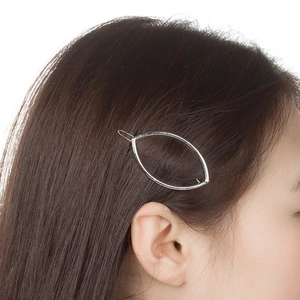 Gros plan sur une pince à cheveux ovale argentée au design épuré sur modèle