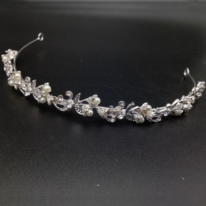 Detailed view of silver bridal tiara featuring white pearls and floral rhinestone patterns