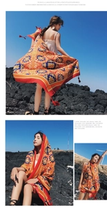 Detail of bohemian orange shawl with blue prints and red tassels for beach sun protection