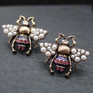 Detailed close-up of vintage bee earrings with pearls, crystals, and blue enamel