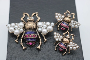 Detailed macro of vintage gold bee jewelry set with pearls and blue enamel finish