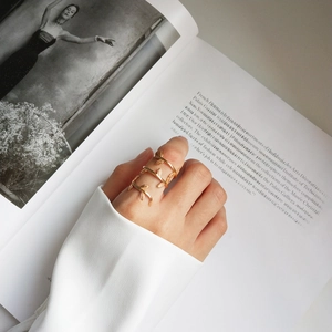 Detailed view of a layered gold vine ring featuring engraved leaf textures on a model's finger