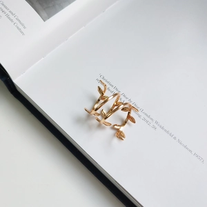 Macro detail of golden vine leaf 925 sterling silver open ring on minimalist book