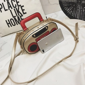 Close-up of vintage radio style handbag with gold metallic finish and red handle detail