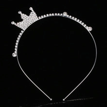 Close-up of silver rhinestone crown headband with sparkling crystals on black background