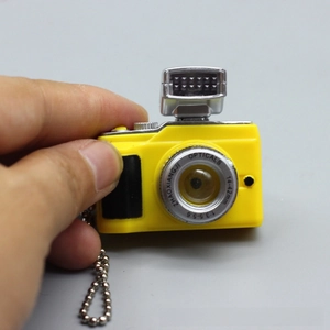 Close-up of a miniature yellow toy camera with a metal bead chain and silver flash