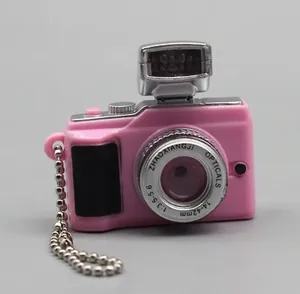 Close-up of pink dollhouse retro camera keychain with metallic beads and optical lens details