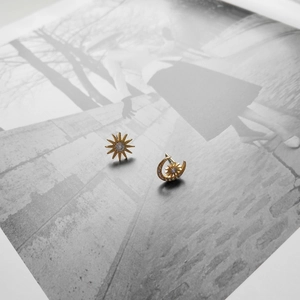 Detail of asymmetric 925 silver star and moon earrings with gold finish and zircon stones