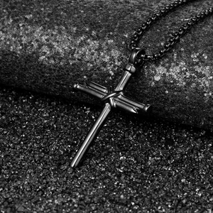 Macro detail of black industrial nail cross pendant with vintage metallic texture