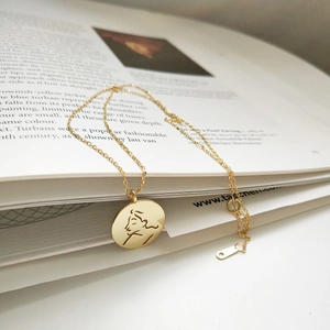 Artistic close-up of 925 sterling silver gold portrait pendant necklace on art book