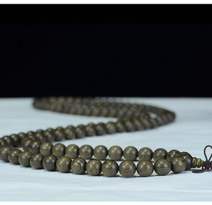 Macro shot of 108 dark Phoebe zhennan wood prayer beads with natural wood grain and textures
