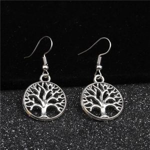 Dettaglio di orecchini pendenti albero della vita in argento con design traforato su nero