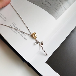 Detailed close-up of a 925 silver Little Prince rose pendant necklace on an art magazine