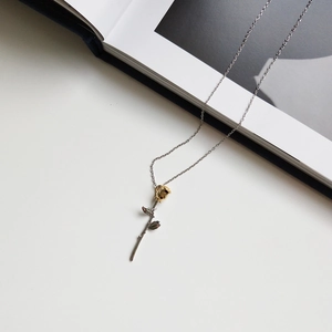 Detailed macro shot of a two-tone rose pendant necklace in gold and silver finish
