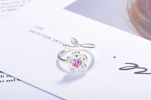 Macro view of cherry blossom ring with pink gemstone and delicate hollow leaf detail