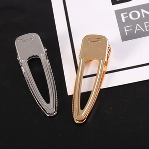 Detail view of minimalist gold and silver cutout metal snap hair clips on black background