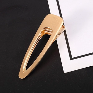 Detailed macro view of a matte gold hair clip showing its smooth brushed metal texture