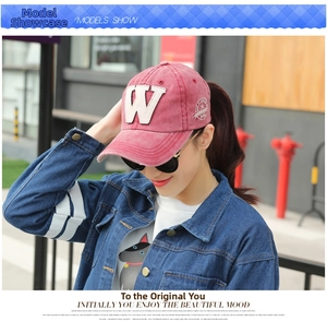 Close-up of a vintage red washed cotton baseball cap with embroidered W patch and side badge