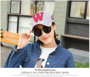 Detail of light gray cotton baseball cap with red embroidered W letter worn with denim jacket