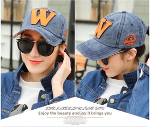 Close-up of washed blue denim baseball cap featuring an orange embroidered W patch
