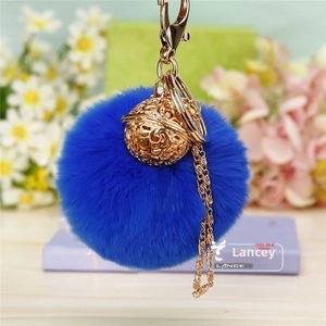 Détail d'un porte-clés en fausse fourrure bleu Klein avec une cloche en métal doré sculpté