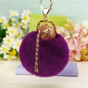 Détail du porte-clés pompon en fausse fourrure violette avec cloche dorée et fermoir mousqueton