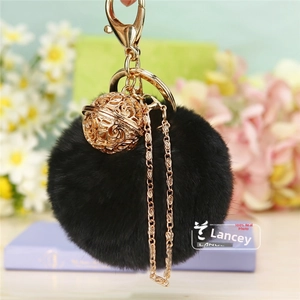 Détail d'un porte-clés pompon noir avec boule métallique dorée et fermoir mousqueton