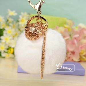Vue détaillée d'un porte-clés en fausse fourrure blanche avec une boule dorée ajourée