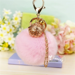 Détail d'un porte-clés pompon en fausse fourrure rose avec grelot doré et clip en métal
