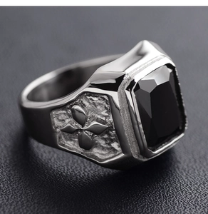 Macro shot of silver ring with black rectangular stone and cross relief detail