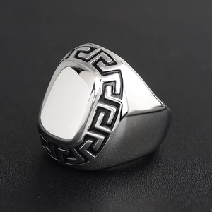 Polished silver titanium men's ring featuring classic Greek key patterns on leather background