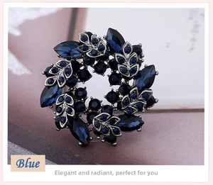Macro shot of circular blue crystal brooch with vintage silver textured leaf details