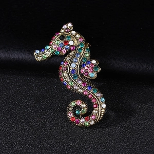 Detailed close-up of a vintage seahorse brooch with colorful rhinestones on a black background