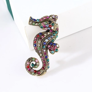 Vintage gold seahorse brooch with multicolored rhinestones on a white jewelry box