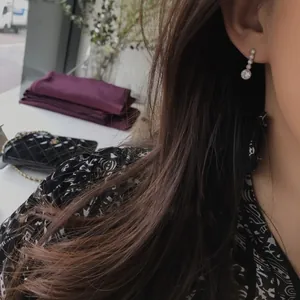 Elegant 925 sterling silver drop earrings with white zircon crystals on a model's ear