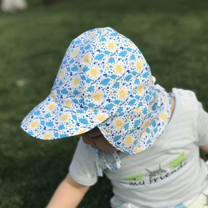 Close-up of kids summer sun hat with neck flap and colorful cartoon prints on grass