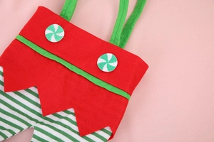 Dettaglio del sacchetto regalo elfo di Natale in feltro rosso con decori di caramelle