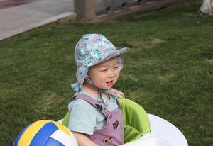 Detail of baby sun hat with neck flap featuring cartoon prints for outdoor sun protection