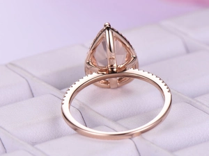 Macro detail of pear-cut pink gemstone ring with rose gold band and pave diamonds
