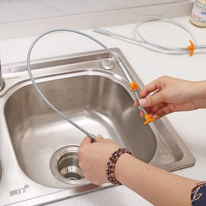 Flexible drain clog remover tool with orange handle picking up debris in kitchen sink