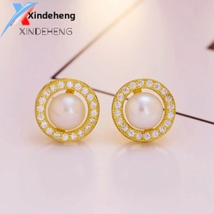 Macro shot of elegant pearl stud earrings with sparkling diamonds and gold settings